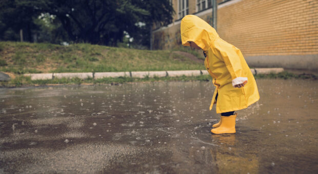 Little boy walking outdoors at rainy autumn day